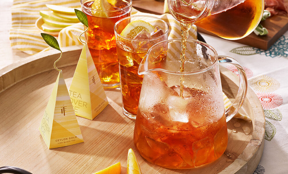 Tea Over Ice small pitcher of  iced tea being poured into lower pitcher filled with ice, with infusers to the side.